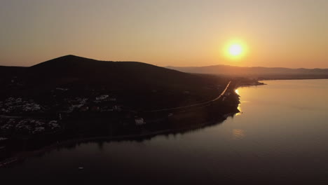 Flying-over-Trikorfo-Beach-with-cottages-and-green-uplands-at-sunset-Greece