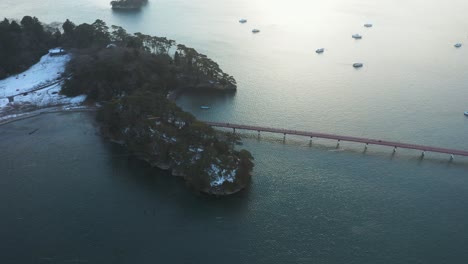 Snow-on-Matsushima,-Aerial-view-of-Fukuurajima-Island-and-Red-Bridge-in-Miyagi