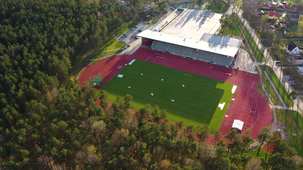 골든 아워 빛과 함께 공중에서 접근하는 트랙 및 필드 스타디움