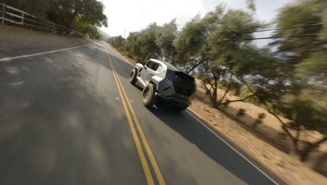 Toma-De-Seguimiento-Fpv-De-Un-Automóvil-De-Aspecto-Futurista-Que-Viaja-Por-Una-Carretera