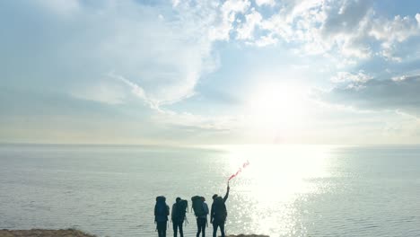 바다 근처의 모래 바위 꼭대기에 서 있는 불 지이를 가진 여행자 들