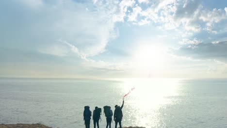 the travelers with fire stick standing on the top of sandy rock near the sea