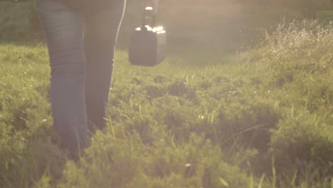 carrying retro portable radio music player in rural countryside field