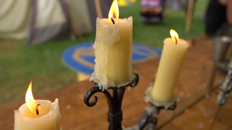 tres viejas velas encendidas sobre candelabros negros colocados sobre una mesa de madera, tiro a cámara lenta