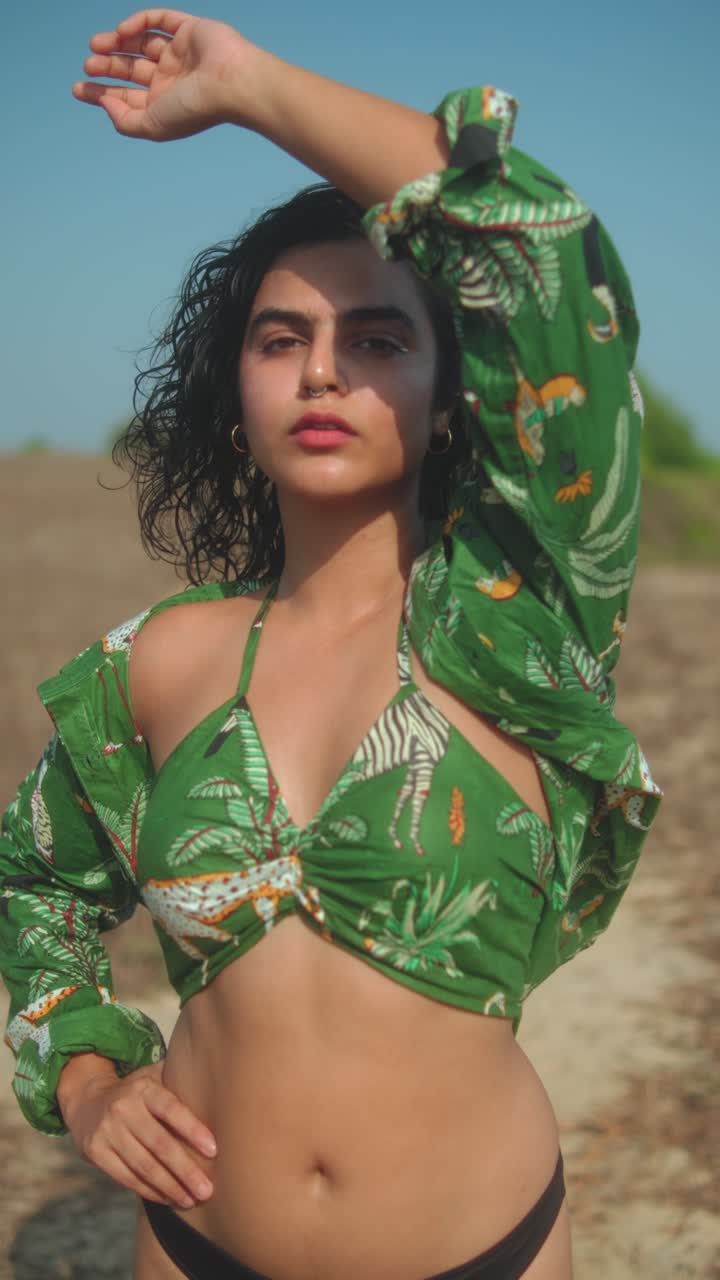 Woman posing in green leaf print bikini top with matching shirt in bright sun