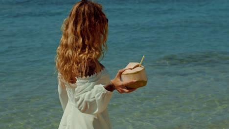 woman on beach with coconut drink