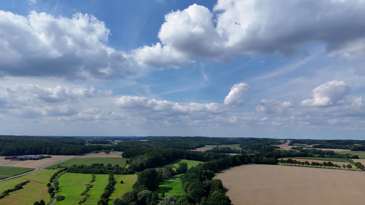 Quiet idyllic landscape in American state of Nebraska. Sunny day with blue sky. Aerial panorama shot. Green forest, cropland and farmlands. Mountain hills in distance. Picturesque scenery in America