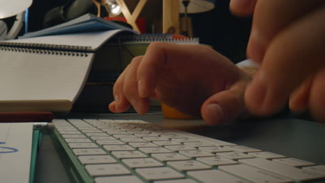 hombre desconocido mecanografiando dispositivo por la noche zoom en. hombre brazos presionando botones de la computadora