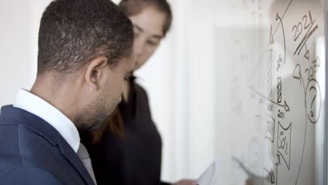 hombre de negocios serio dibujando gráfico en tablero de vidrio