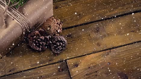 falling snow with christmas pine cone decoration on wood