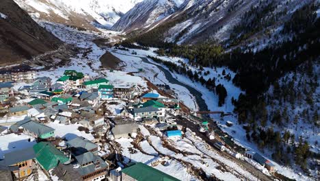 una toma aérea de las casas de madera tradicionales de chitkul rodeadas de gruesas capas de nieve.