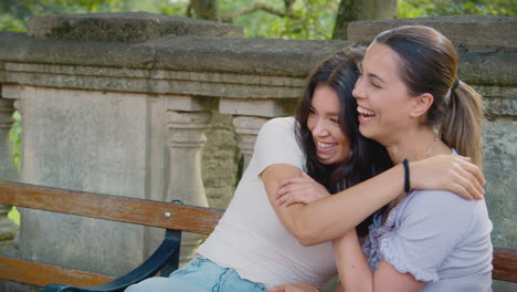 same sex female couple sightseeing around oxford uk sitting on bench and hugging