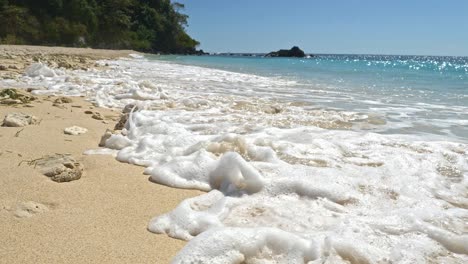 Waves-crashing-on-tropical-sandy-beach,-slowmotion,-Nosy-Be,-Nosy-Fanihy,-Madagaskar,-Africa