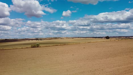 Paisaje-Rural-Soleado-Con-Vastos-Campos-Abiertos-Y-Un-Cielo-Azul-Vibrante-Lleno-De-Nubes-Esponjosas