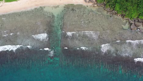 Tiro-De-Seguimiento-De-Arriba-Hacia-Abajo-Que-Captura-El-Arrecife-Bordeado-De-Houshi-Y-El-Hermoso-Agua-De-Mar-Turquesa-Con-Olas-Rompiendo-En-La-Costa-En-La-Cueva-De-Enanos-Negros-En-La-Isla-De-Xiaoliuqiu-Lambai,-Taiwán