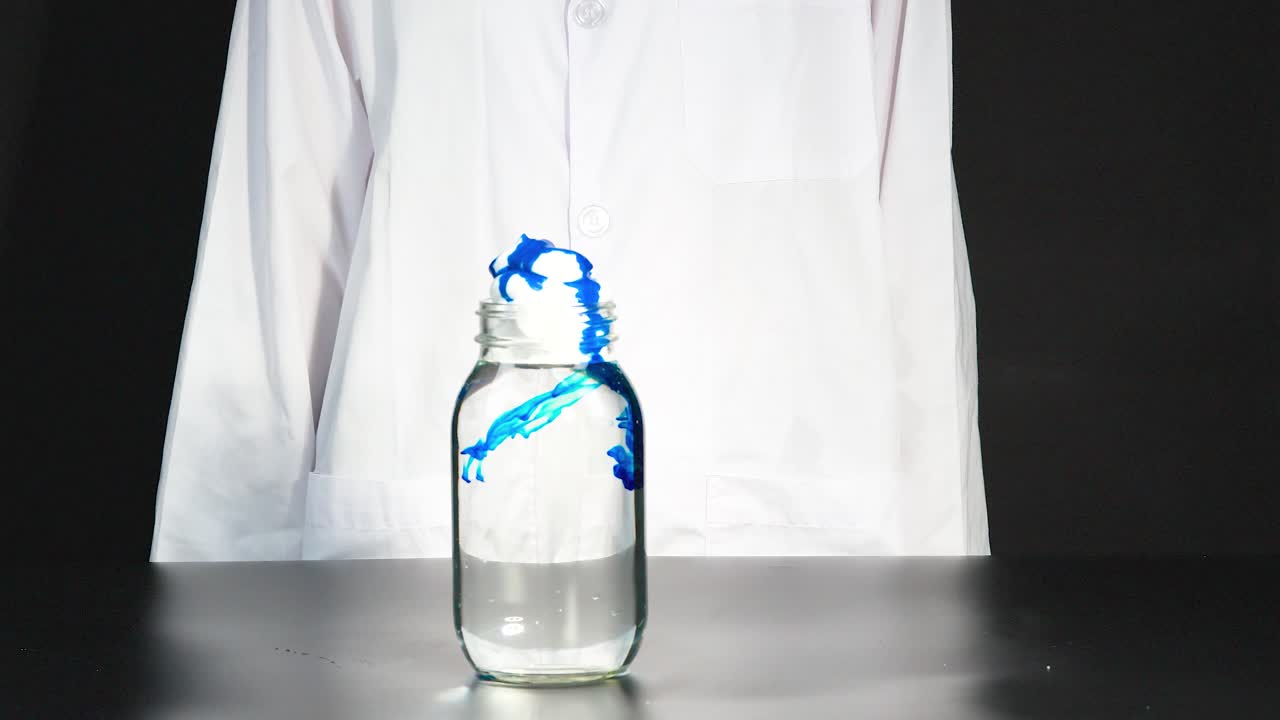 una vibrante reacción química se desarrolla en un vaso, mostrando un tinte azul giratorio en un entorno de laboratorio