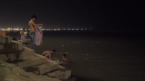 men and boy bathing in the ganges at night