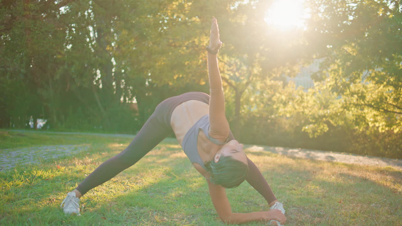 mujer deportiva haciendo curvas en el parque sunbeams. mujer atleta flexible estirando la espalda