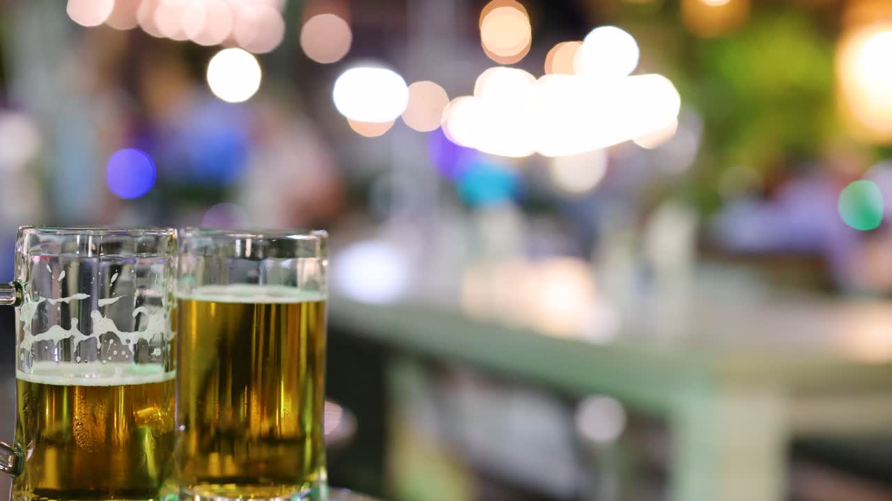 dos vasos de cerveza con luces nocturnas borrosas