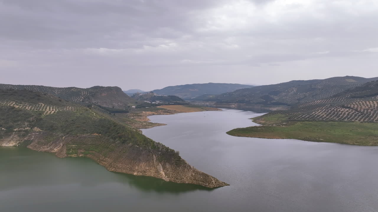 Flight on a grey green gloomy still day across Spain's huge Iznajar reservoir