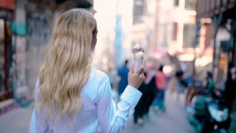 young beautiful girl eats ice cream while walking at narrow street in europe