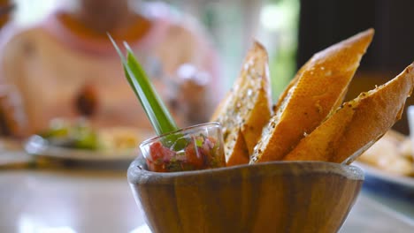 close up shot of a plate of bread loaves with happy asian woman in blurred background in restaurant. healthy eating and diet concept.