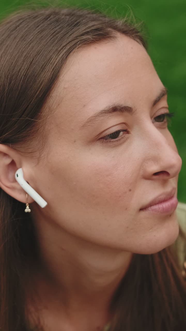Primo piano di giovane donna che ascolta con un auricolare all'aperto