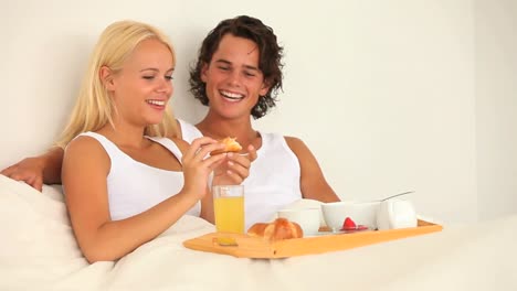 pareja disfrutando de su desayuno en la cama