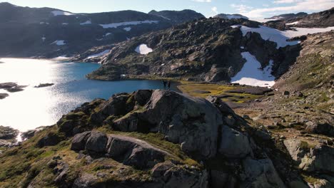 personas de pie en la cima de la colina sobre un lago natural en el parque nacional hadrangervidda en noruega disparos de drones