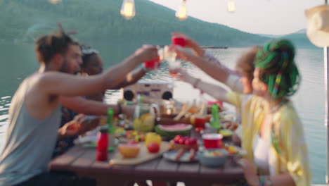 group of friends toasting with drinks at lake party