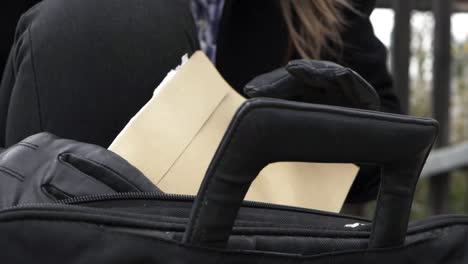 mujer de negocios sacando documentos y sobres en maletín primer plano