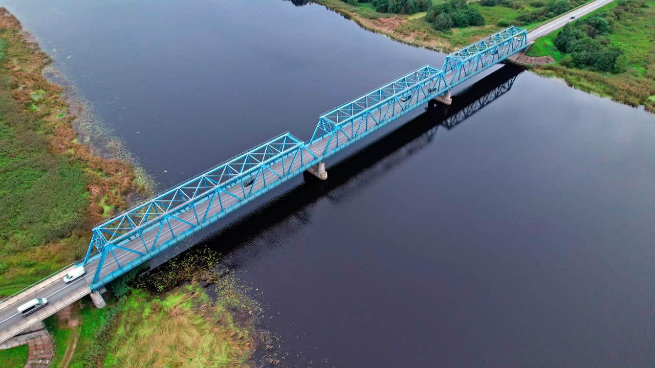 Vibrant blue bridge over tranquil waters in Latvia viewed from above