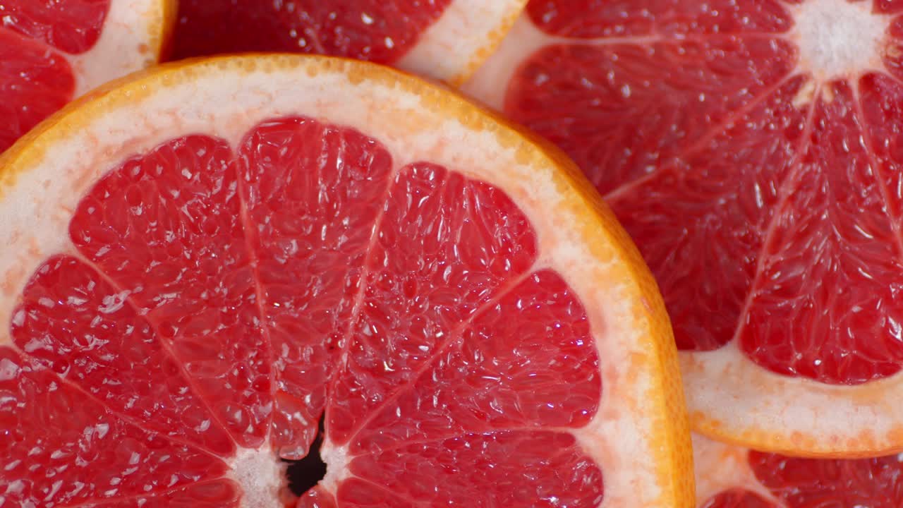 Round slices of fresh grapefruit slowly rotate.