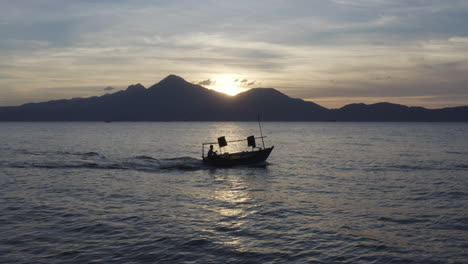 Fishing-Boat-motors-out-to-ocean-at-sunset-against-a-beautiful-landscape-in-Asia