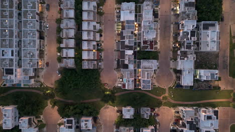zenith drone shot zooming down shot of rooftops at a gated community neighborhood in the evening