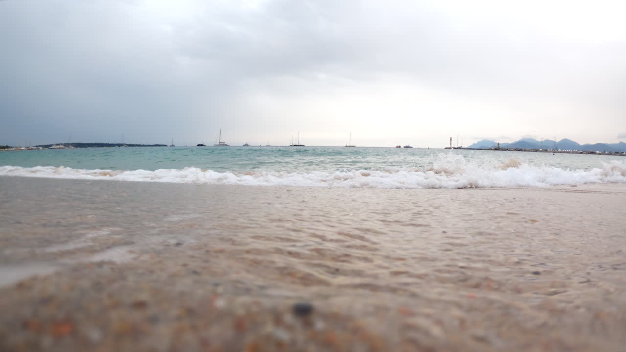 Waves hitting the shore on the beach on a cloudy day