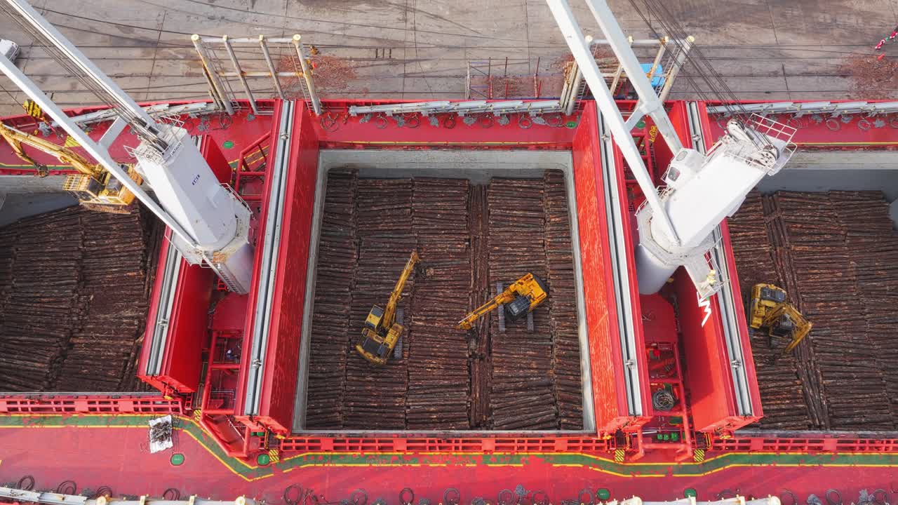 우루과이 강을 따라 화물 선박이 크레인과 발굴기와 함께 목재를 고 있습니다.