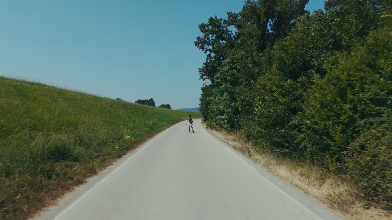 A girl on roller skates is rolling down the road next to the forest and the embankment