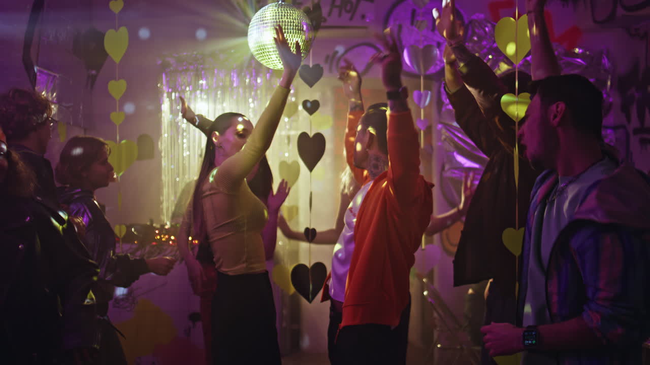 Active people moving dancefloor under disco ball lights. Energetic couple party