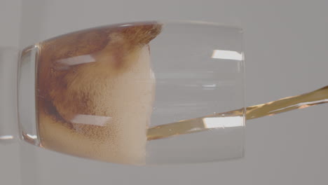 vertical video - cola being poured into glass against a white studio background