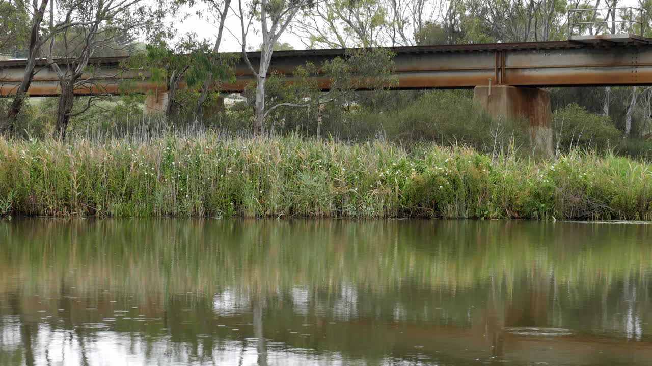 배경에 녹슨 철교가 있는 고요한 강에 가벼운 비
