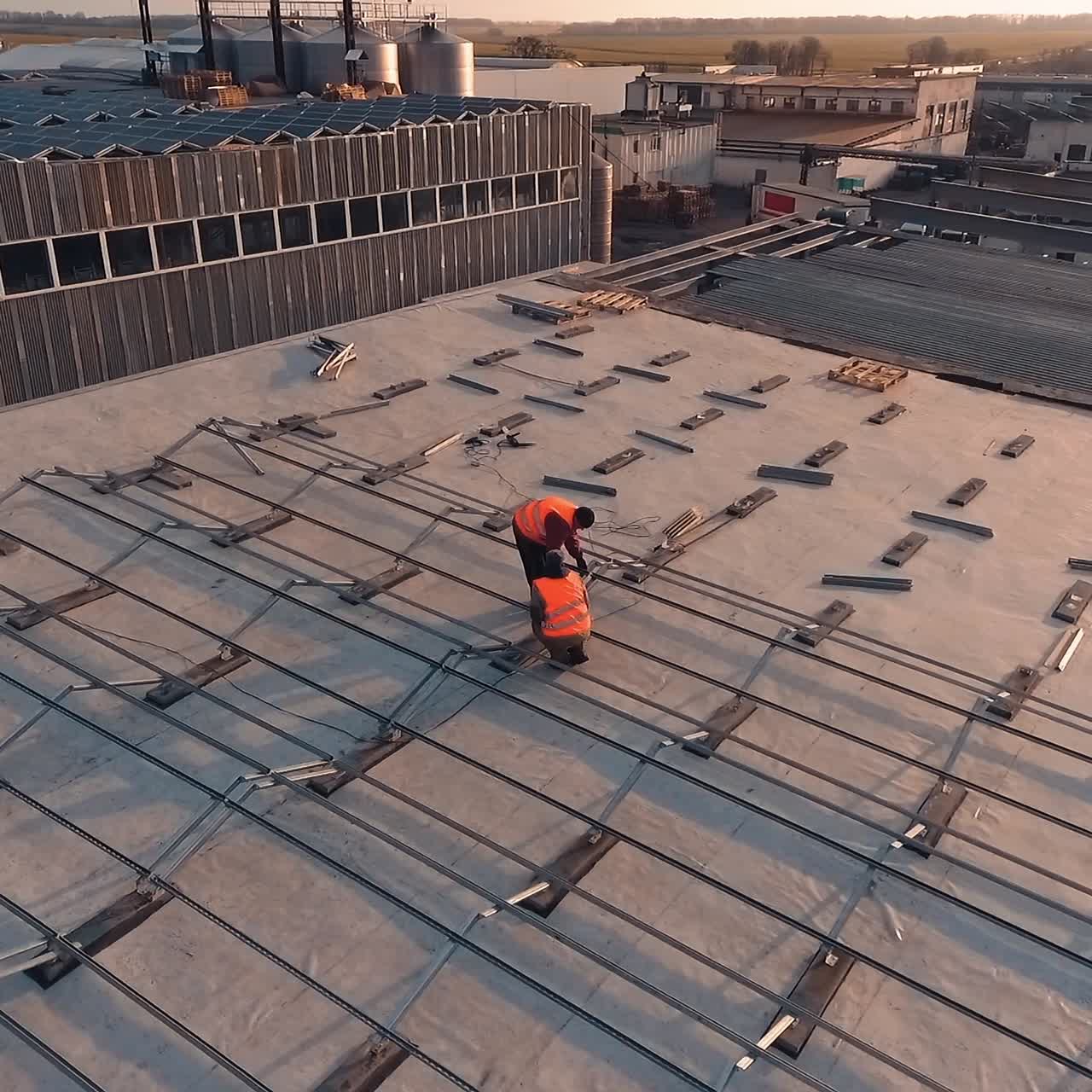 Installation solar panels on a roof. Workers put metal constructions before installing solar panels on a roof of a big building. Top view.