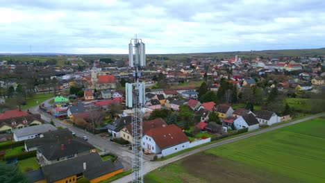 volando por torre celular y casas en el barrio durante el día en el campo rural