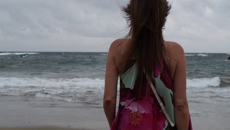 toma cinematográfica al amanecer de una mujer admirando las olas del océano en la playa de las canteras