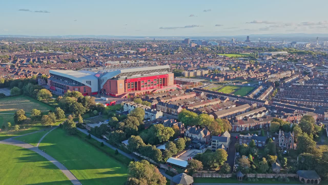 Stunning aerial drone footage of Liverpool FC’s iconic Anfield stadium in Liverpool, England, filmed during sunset. The golden-hour light enhances the famous football ground, surrounding cityscape