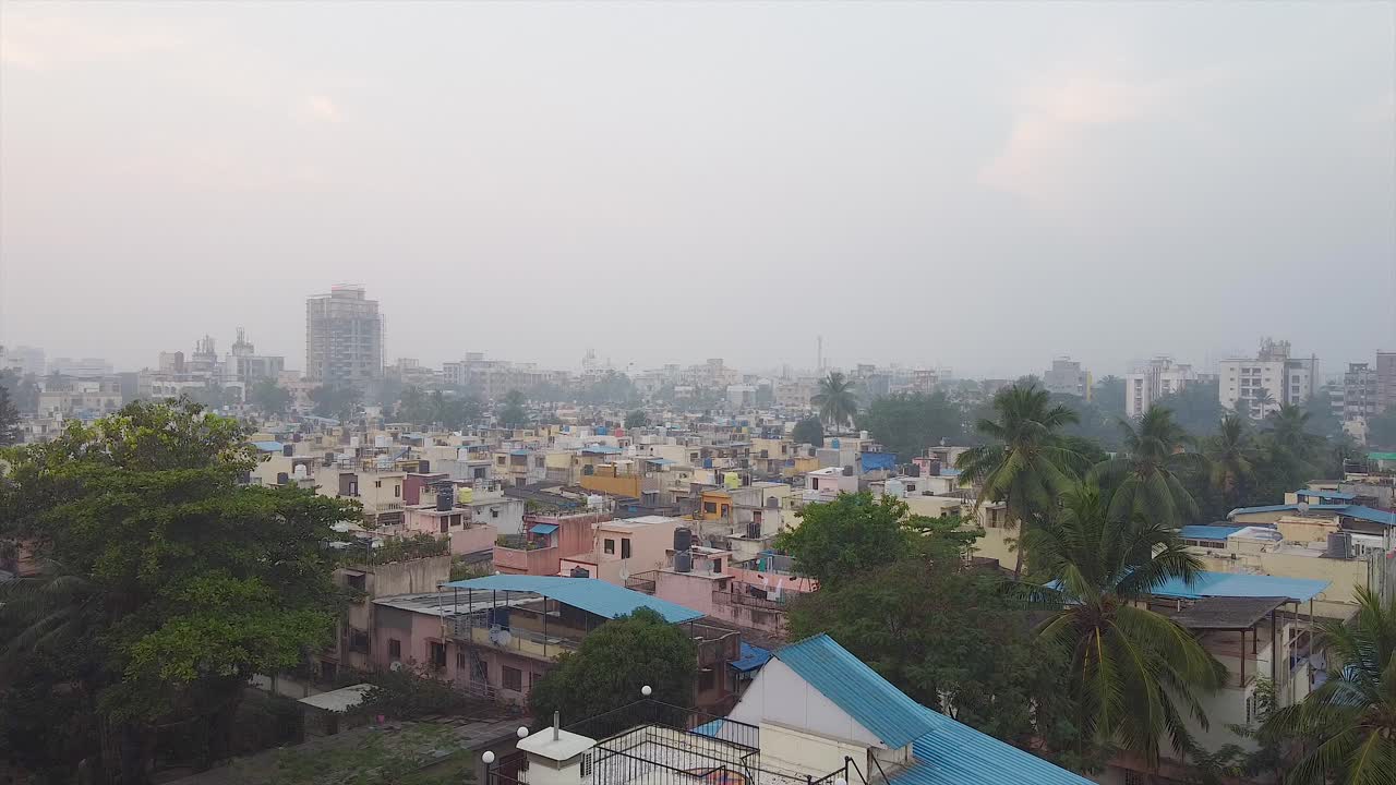 Vista aerea di un quartiere urbano di una grande città, con edifici aziendali, come sfondo video. Ripresa cinematografica con drone di un piccolo insediamento aziendale in condizioni di nebbia a Mumbai, India, come sfondo video.