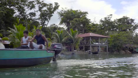 Blick-Von-Einem-Boot-Auf-Eine-Dorfhütte-Auf-Stelzen-Entlang-Eines-Flusses-In-Guatemala-1