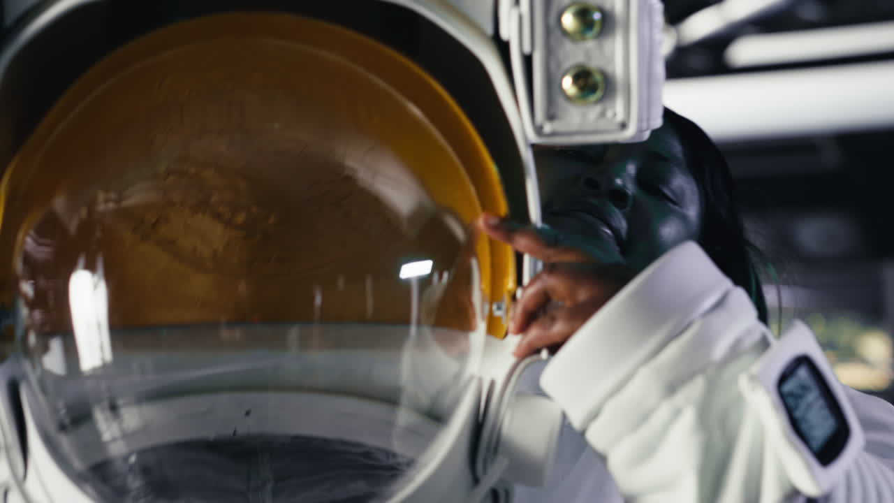 Joyous astronaut putting helmet on inside high tech spacecraft