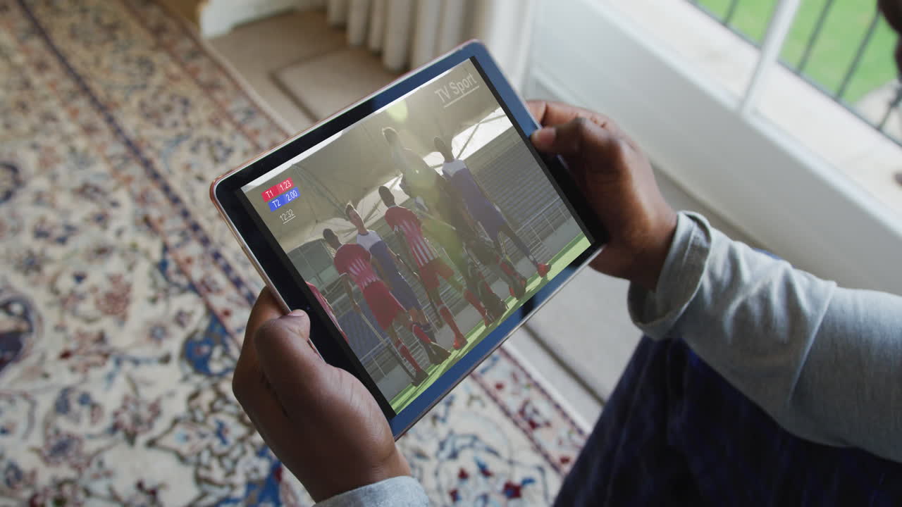 compuesto de un hombre sentado en casa viendo un partido de hockey en una tableta