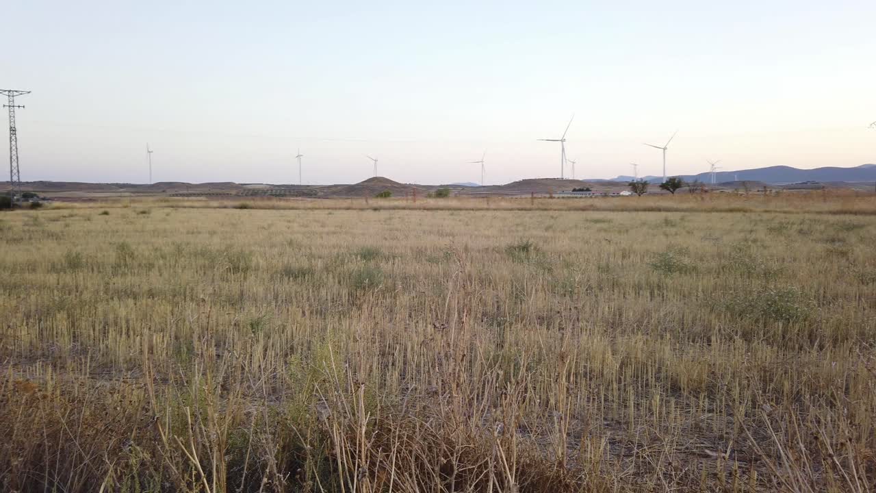 Electricity pylons and wind turbines against an evening sky in rural Spain